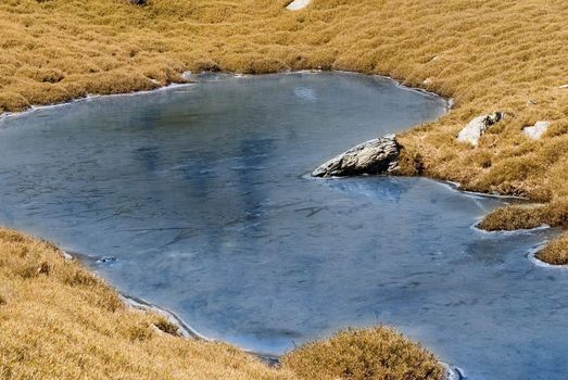 Beautiful strange iced pond surface and rock.