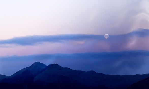 Moon rised and shining over the high mountain.