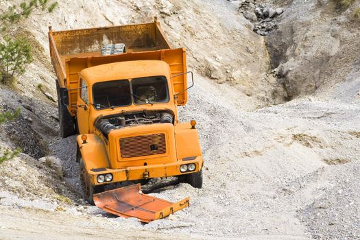 Old, abandoned, broken down orange truck in quarry.