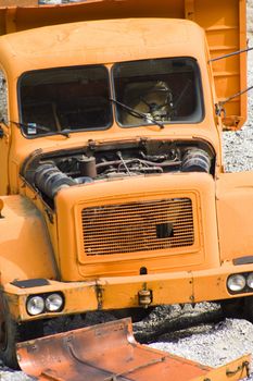 Old, abandoned, broken down orange truck in quarry.