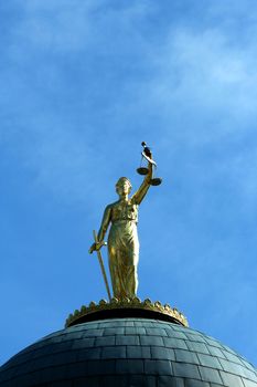 A Lady Justice statue against blue sky
