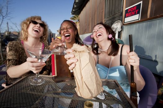Three women outside a house drinking alcoholic beverages