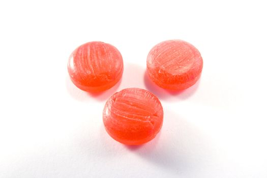 Three red sweets in a triangle on a white background