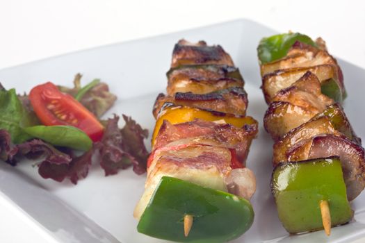 shashlik on a plate with a tomato and salad leaf