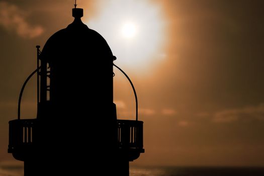 silhoutte of lighthouse captured with the sun behind it
