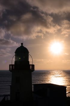 silhoutte of lighthouse captured with the sun behind it