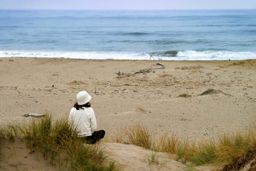 young woman sitting at the beach looking over the ocean
