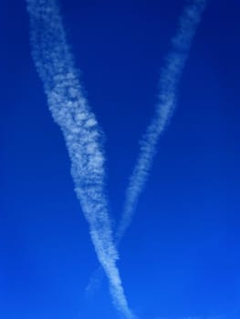 clouds from airplanes building a V in the sky