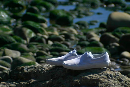 A pair of white shoes left alone on the beach