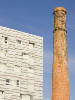 architecture contrast of a new building against one old chimney 