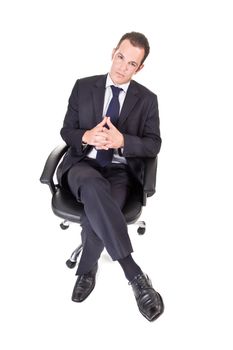 A young businessman, sitting on an office chair, with hands crossed.