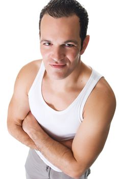 A handsome young man after working out, wearing a sleeveless shirt, standing with arms crossed with a smile.