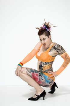 Adult caucasian woman with tattoos squatting on floor.