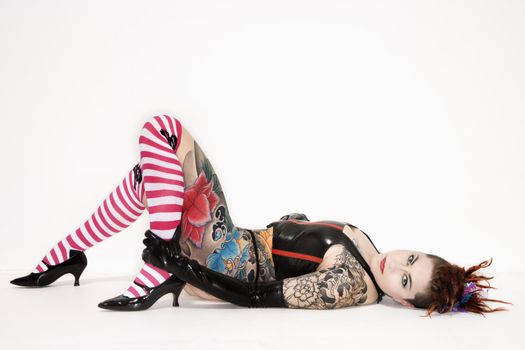 Adult caucasian woman with tattoos lying on floor.