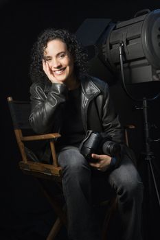 Woman smiling and holding camera in studio setting.