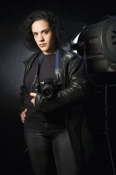 Woman holding digital camera in studio setting.