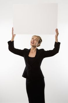 Caucasian businesswoman standing holding blank sign above head.