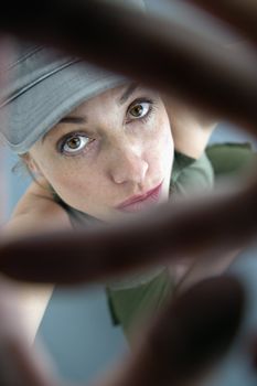 Caucasian woman looking up at viewer through hands.