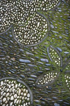 Outdoor mosaic made of pebbles and rocks in shape of flowers.