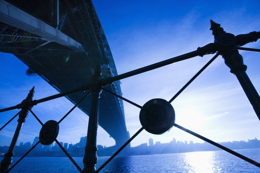 Low angle view at dusk from under Sydney Harbour Bridge in Australia with view of skyline and harbor.