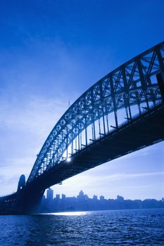 Sydney Harbour Bridge at dusk with view of distant skyline and harbour in Sydney, Australia.