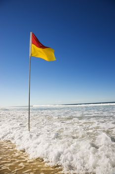 Red and yellow flag on beach in Surfers Paradise, Australia.
