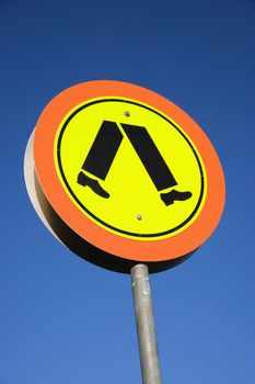Pedestrian crosswalk sign with blue sky in Australia.