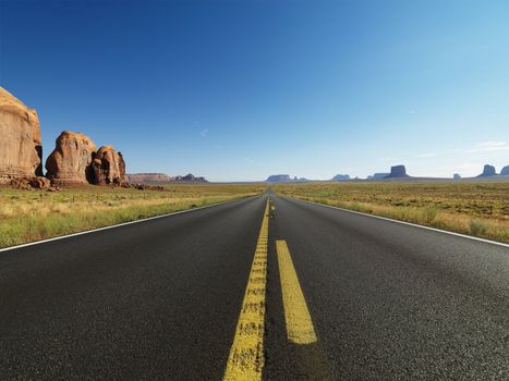 Open highway in scenic desert landscape with distant mountains and butte land formations.