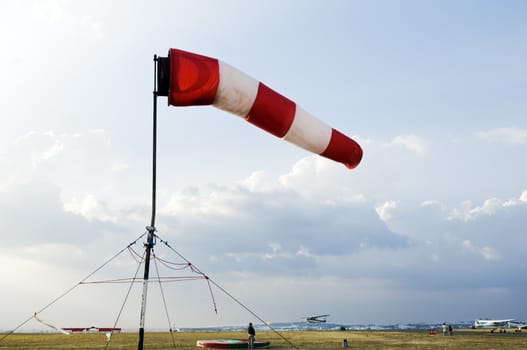 A red and white windsock flying in the wind to signal direction on an airfield