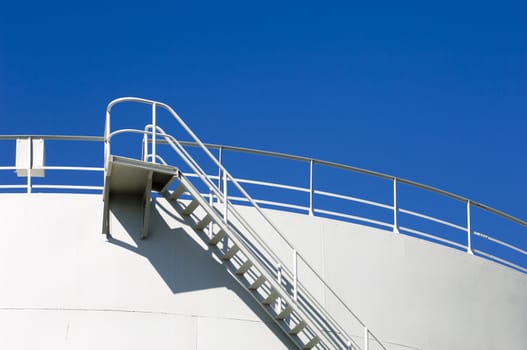 Oil reservoir detail with access ladder against a blue sky