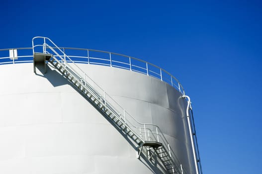 Oil reservoir detail with access ladder against a blue sky