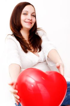 Pregnant woman presenting heart shaped baloon over white