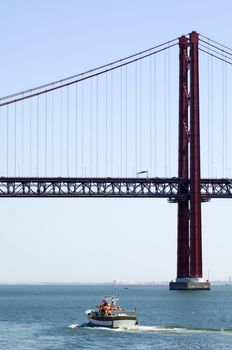 25th of April (25 de Abril in Portuguese) bridge in Lisbon, Portugal, with small fishing boat below