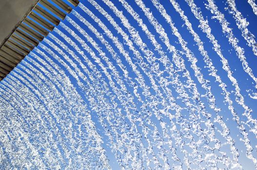Abstract of lines of cascading water, with a blue sky background.