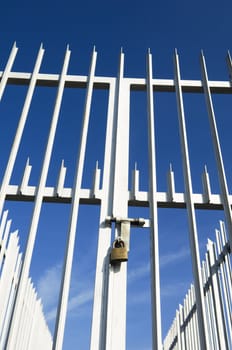 Modern spiked fence and gate closed with a padlock