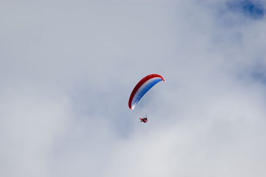 Man enjoying the ride in a blue white red paraglider