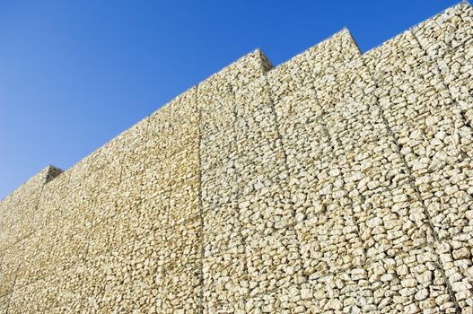 Safety wall made of stacked meshed boxes of stones