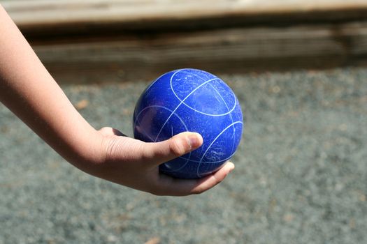A Hand holding a blue bocce ball