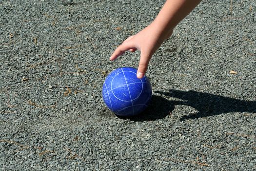 A hand reaching for a bocce ball