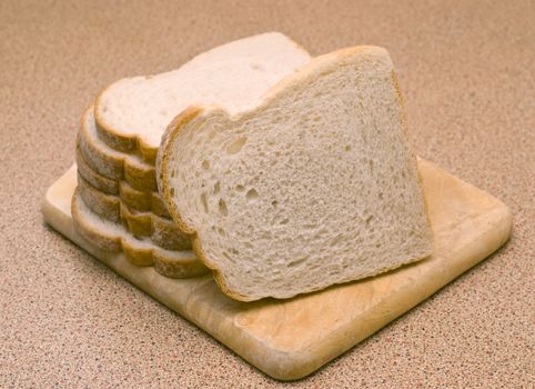 fresh sliced white bread placed ontop of a chopping board on a counter to.
