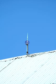 Lightning rod on top of a barn against a blue sky
