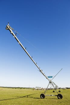 Resting irrigation pivot in a green grass field near a small village. Alentejo, Portugal