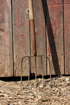 A Pitchfork leaning on a old red barn