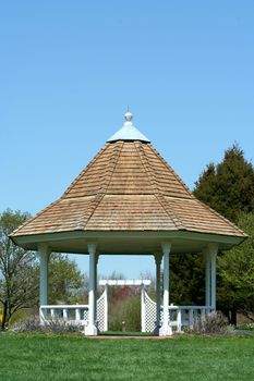 A White gazebo in a park with blue sky