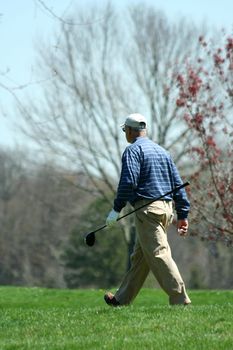 A Male golfer walking on a golf course