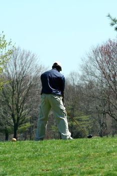 A Male golfer teeing off on a ball