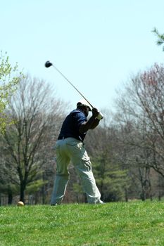 A Male golfer teeing off on a ball