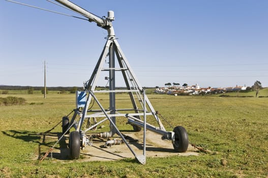 Irrigation pivot axis in a green plane near a small village
