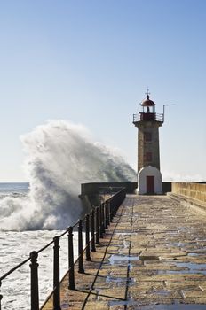 Huge waves breaking against the base of a lighthouse
