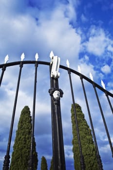 Old iron gate against a blue cloudy sky
